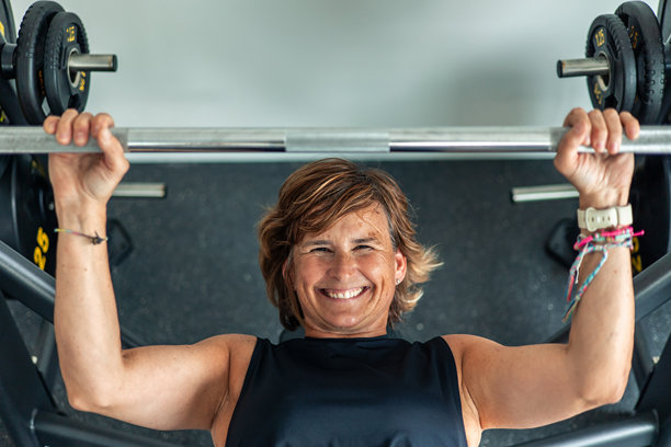 老年妇女在健身房做杠铃卧推图片 老年妇女在健身房做杠铃卧推图片下载