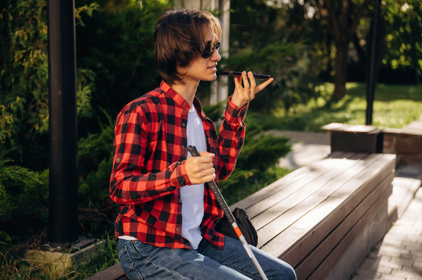 坐着打电话的年轻盲人小伙子在户外城镇图片 坐着打电话的年轻盲人小伙子在户外城镇图片下载