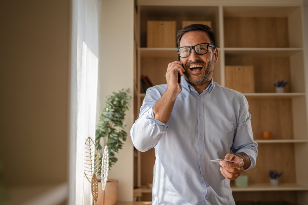 快乐的男人一边打电话一边拿着信用卡图片 快乐的男人一边打电话一边拿着信用卡图片下载