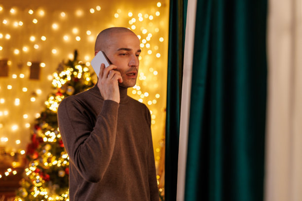 今晚在家,男人在圣诞灯旁打电话,营造出舒适温馨的节日氛围图片 今晚在家,男人在圣诞灯旁打电话,营造出舒适温馨的节日氛围图片下载