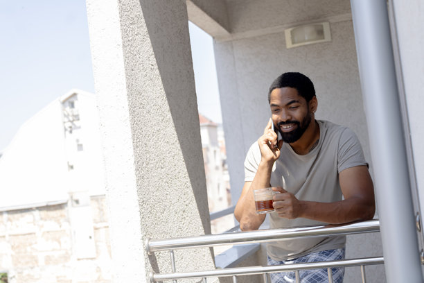 男人在阳台上边喝咖啡边享受地打电话图片 男人在阳台上边喝咖啡边享受地打电话图片下载
