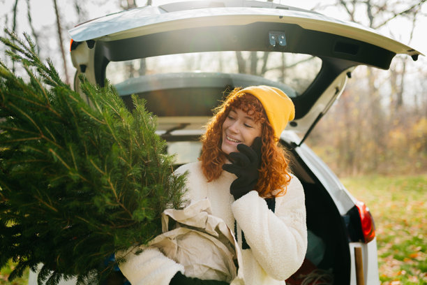 女人在森林里抱着圣诞树打电话图片 女人在森林里抱着圣诞树打电话图片下载