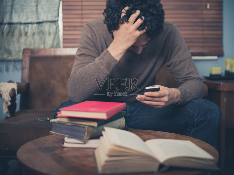 沮丧的学生使用他的智能手机正版图片素材