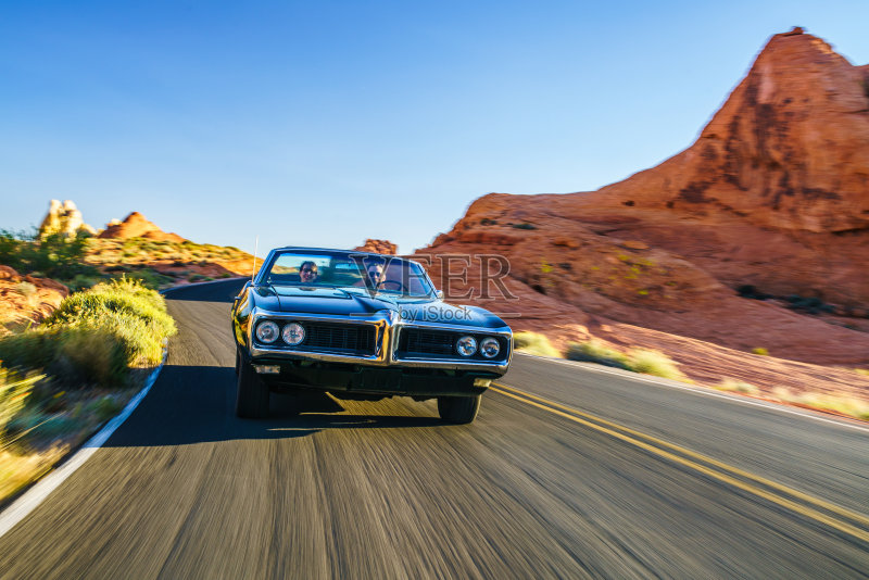 一对情侣开着一辆很酷的老爷车穿越沙漠正版图片素材