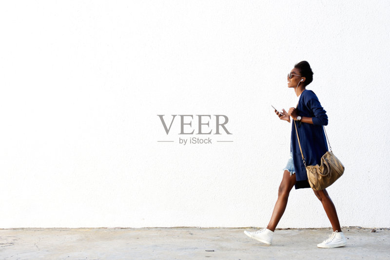 时髦的黑人女人在用手机听音乐正版图片素材