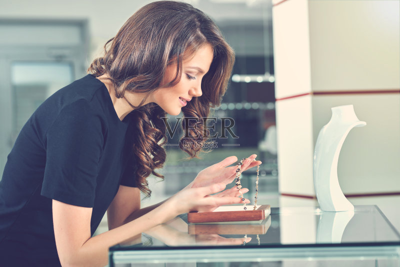 有魅力的女人手里拿着并看着项链。正版图片素材