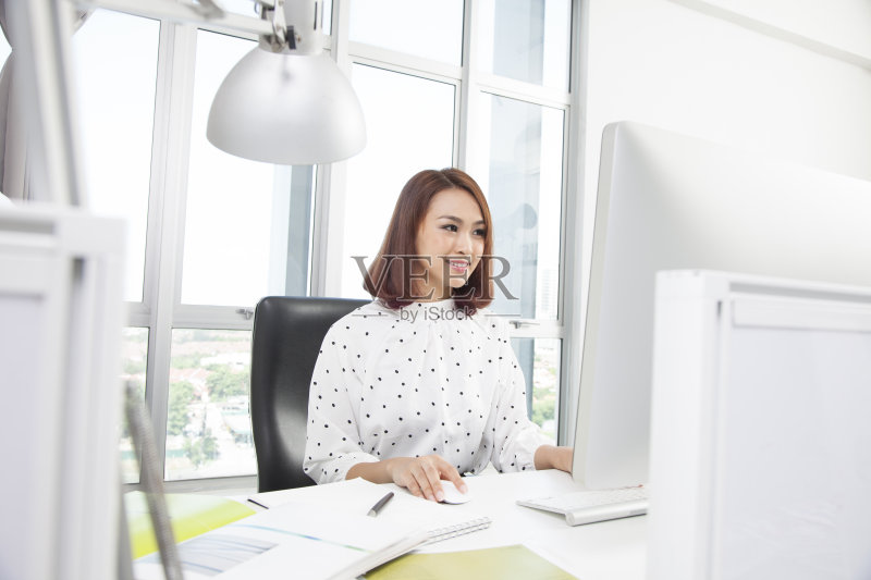 微笑的亚洲女商人在办公桌旁工作正版图片素材