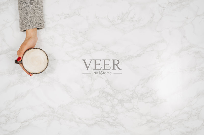 女人双手捧着咖啡放在五颜六色的桌子上,俯视图正版图片素材