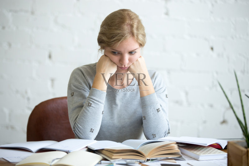 一个疲惫的女学生坐在课桌前正版图片素材