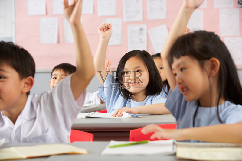 微笑的女孩在其他中国学生中举手正版图片素材
