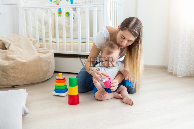 年轻的母亲在地板上玩,教她的小男孩正版图片素材
