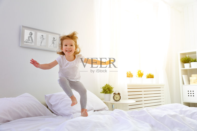 快乐的小女孩蹦蹦跳跳玩床正版图片素材