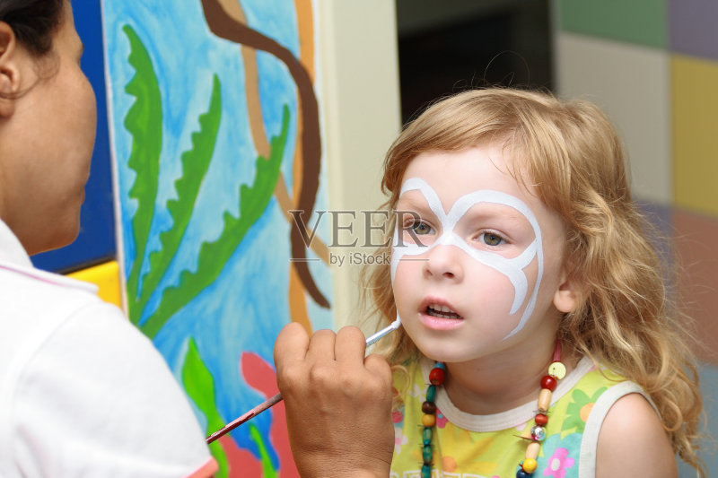 一个女人在小女孩脸上画面具正版图片素材