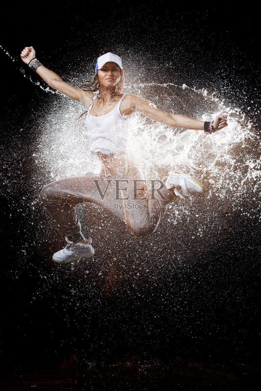 穿着运动服的年轻女子在飞溅的水中跳跃正版图片素材