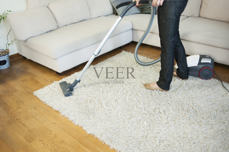 在房间里用吸尘器清洁地毯的女人正版图片素材