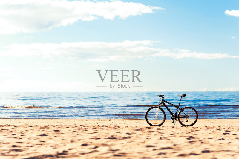 一辆自行车站在沙滩上的蓝色海景背景。正版图片素材