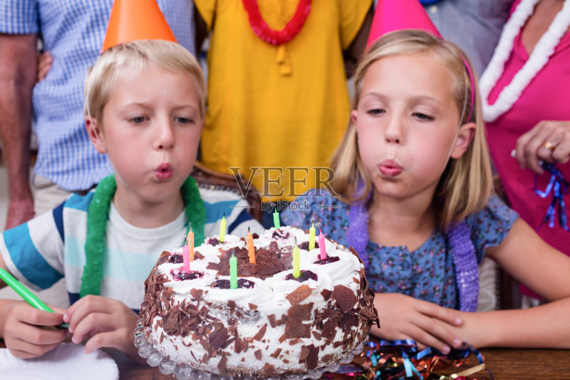 兄弟姐妹在生日派对上吹蜡烛正版图片素材