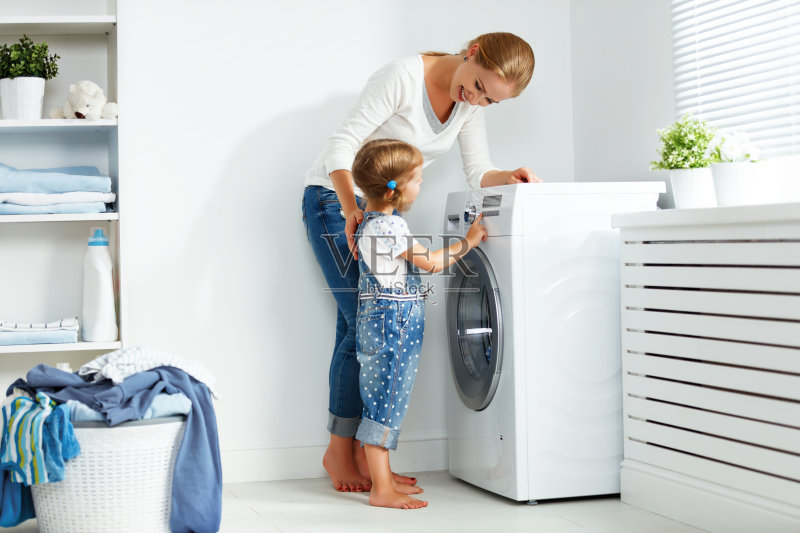 家庭母亲和孩子女孩在洗衣机附近的洗衣房正版图片素材