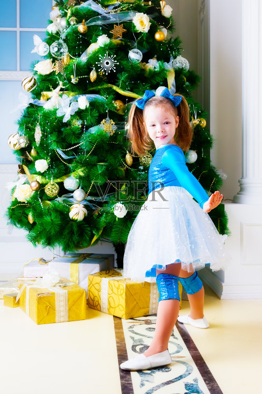 穿着蓝色裙子的女孩站在圣诞树旁正版图片素材