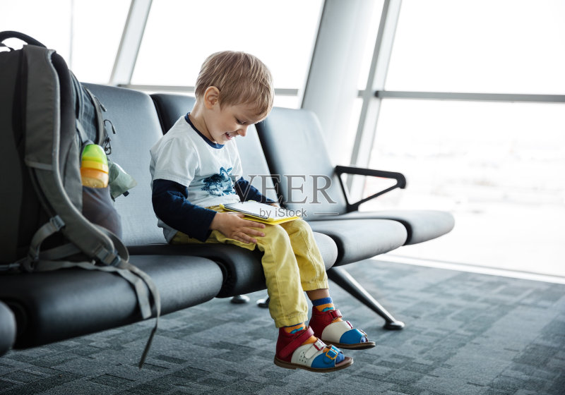小男孩在机场玩平板电脑正版图片素材