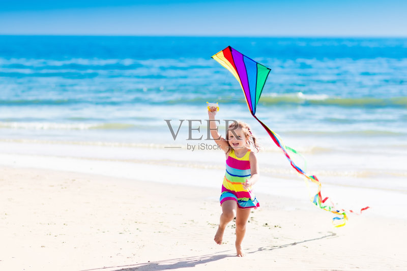 孩子在热带海滩上放风筝正版图片素材
