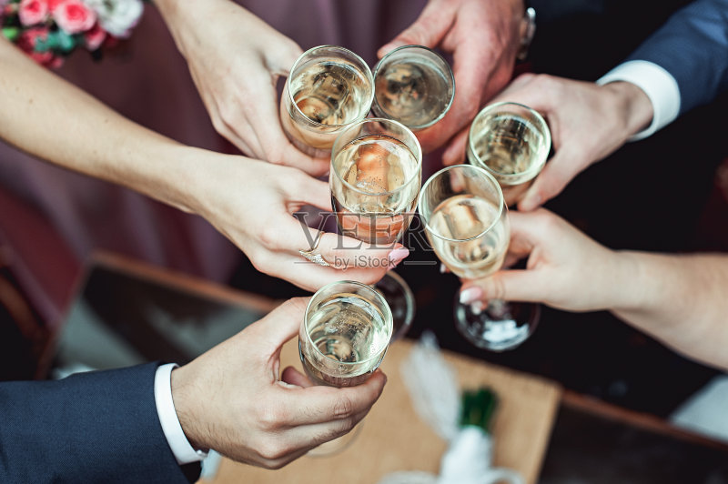 人们手里拿着盛着白葡萄酒的玻璃杯。婚礼。正版图片素材