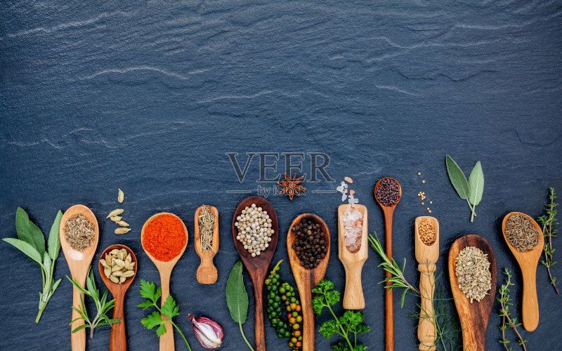 木勺里装着各种香料和药草。在黑石上铺上香料配料辣椒,胡椒,大蒜,百里香,牛至,肉桂,八角,肉豆蔻,肉豆蔻,鼠尾草和欧芹。正版图片素材