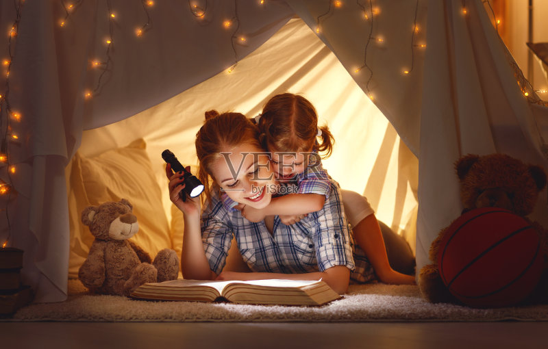 母亲和孩子在睡觉前拿着一本书和一个手电筒正版图片素材