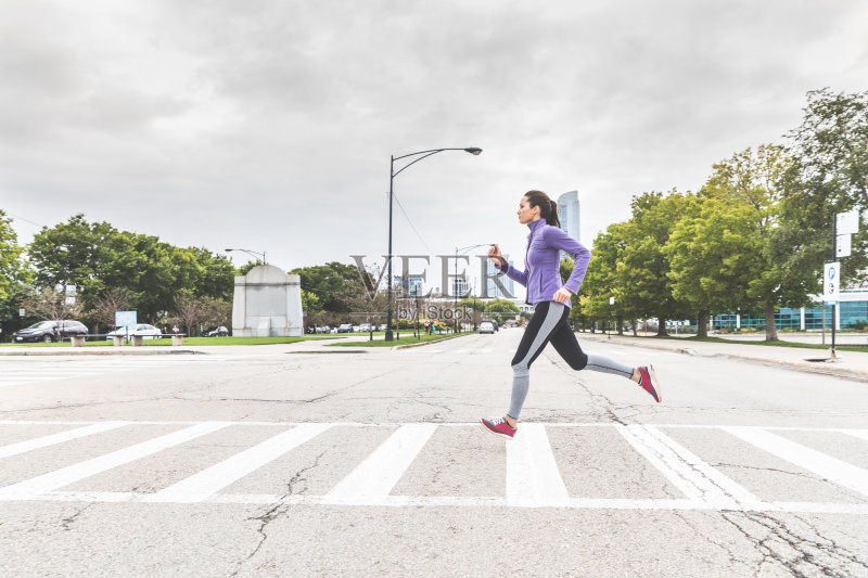 在芝加哥,一名女子慢跑并踩着斑马过马路正版图片素材
