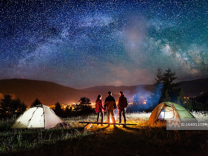 情侣徒步旅行者站在露营篝火旁的后视图照片摄影图片
