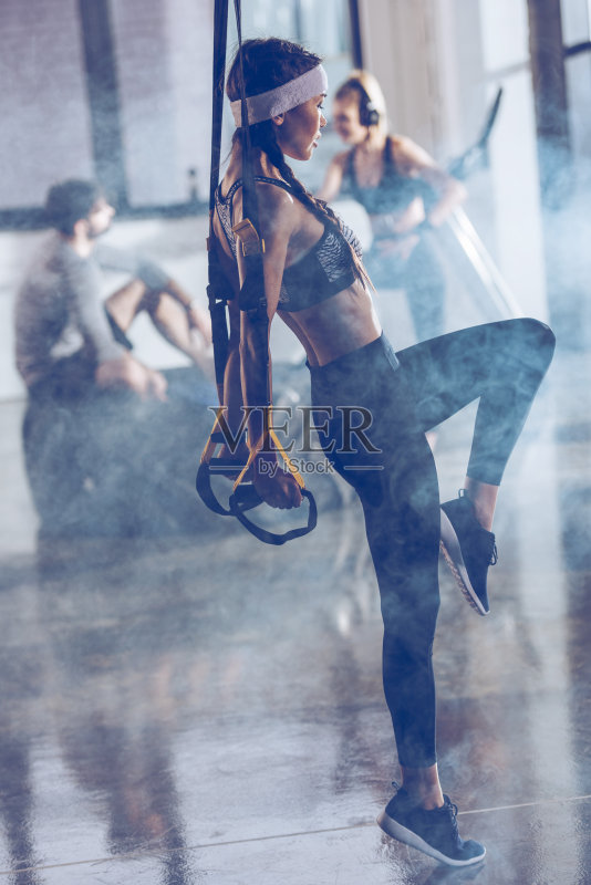 侧面的运动女性锻炼与TRX健身房设备正版图片素材