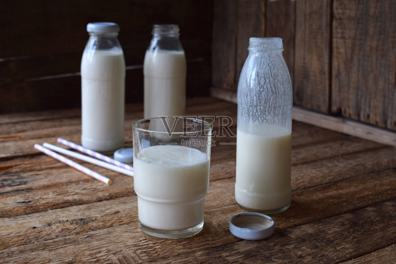 酸乳饮料或酸奶瓶,来自开菲尔谷物和牛奶在木制背景。在自然光下拍摄正版图片素材