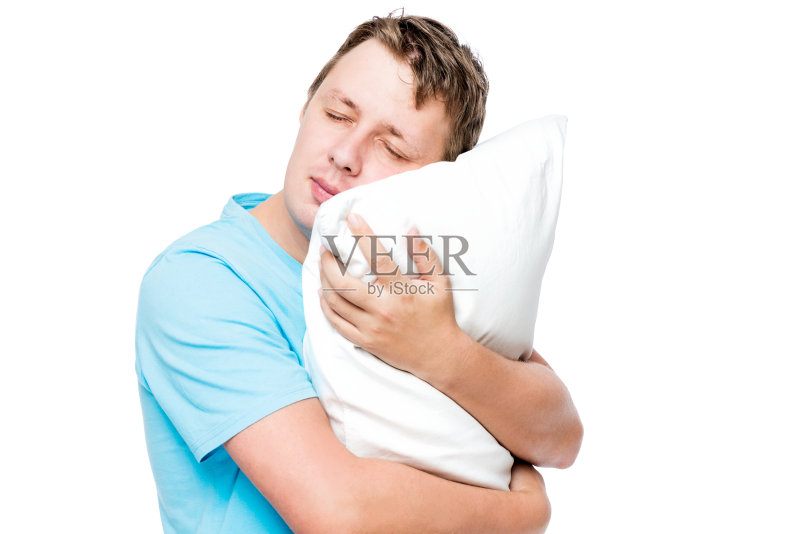 在白色的背景下,睡着的男人抱着柔软的枕头正版图片素材