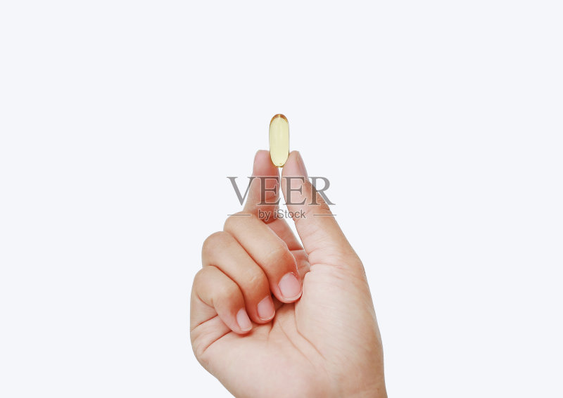 手持黄色鱼油胶囊孤立在白色背景上。正版图片素材