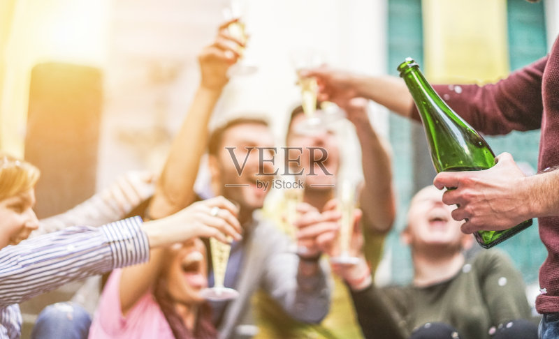 快乐的朋友庆祝喝香槟和聚会户外-年轻的学生有乐趣在日落-青年和fest概念-柔软的焦点右手与瓶子-温暖的对比过滤器正版图片素材