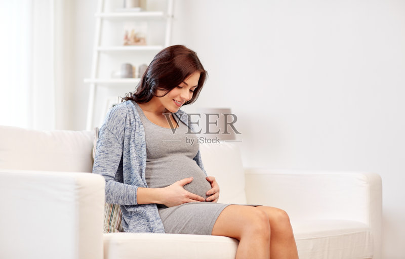 快乐的孕妇坐在家里的沙发上正版图片素材