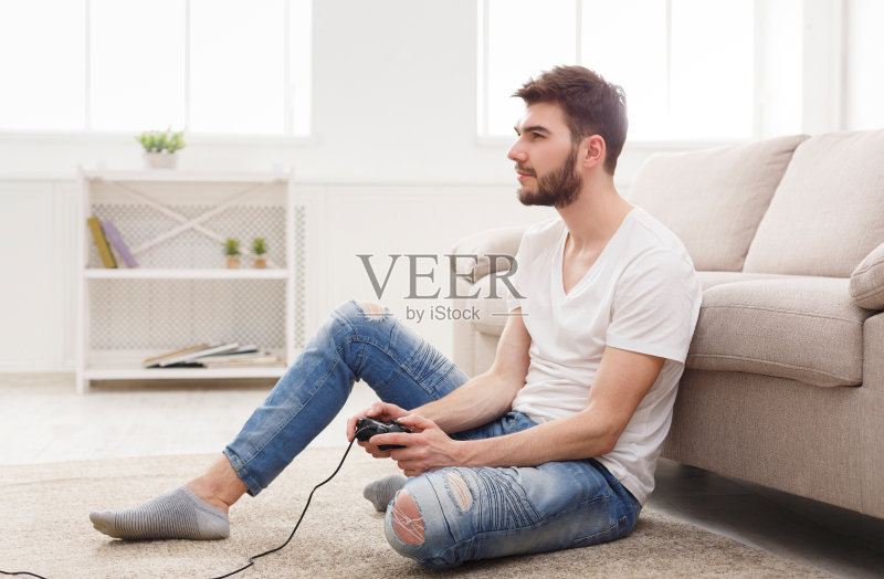严肃的年轻人在家玩电子游戏正版图片素材