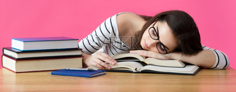 在书桌前睡觉的疲惫的学生照片摄影图片