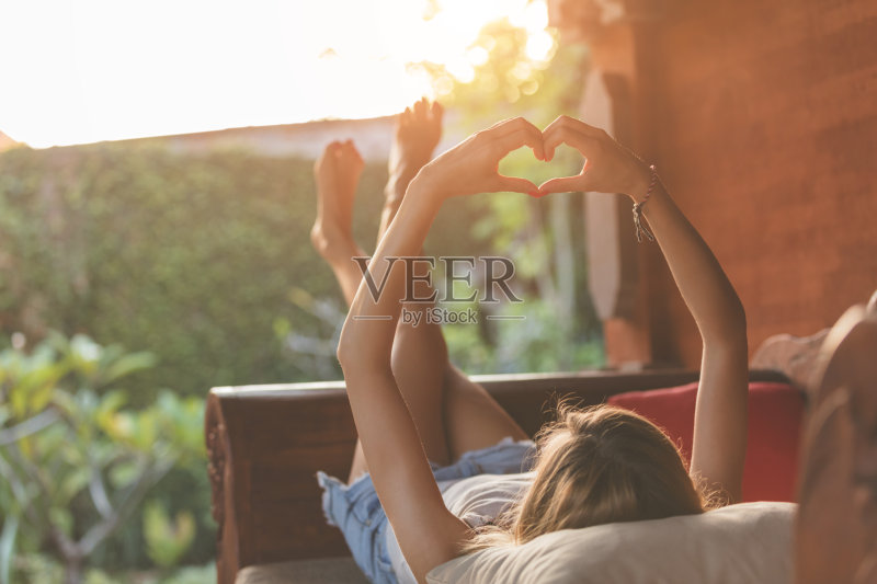 女孩躺在花园的沙发上,手里拿着一个心形的。正版图片素材