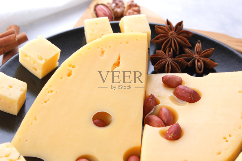 硬奶酪,黑色盘子上有洞的奶酪,白色背景上有蜂蜜的奶酪,浅色背景上有坚果的奶酪片,有奶酪、蜂蜜和坚果的圣诞晚餐,肉桂棒和一个桶正版图片素材