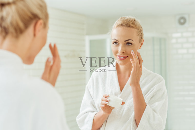 穿着浴袍的女人正在擦面霜正版图片素材