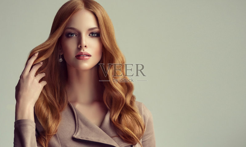 年轻,红发美丽的模特正在触摸自己的长,卷曲,整齐的头发。优秀的头发。正版图片素材