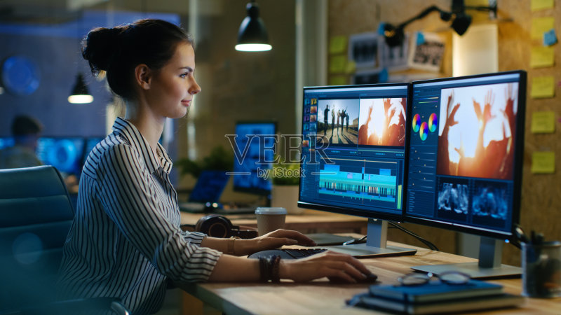 美丽的女性视频编辑工作与镜头在她的个人电脑,她的工作在创意办公室工作室。正版图片素材