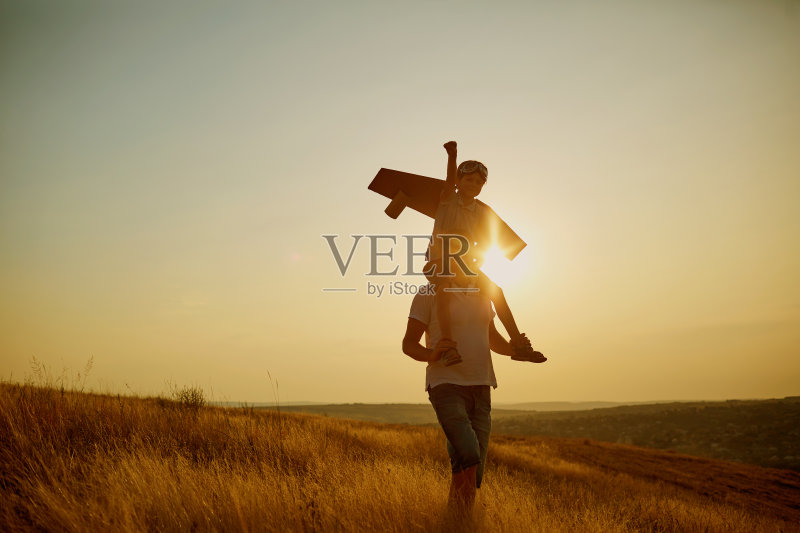 父亲和他的儿子穿着飞行员服在日落的大自然。正版图片素材