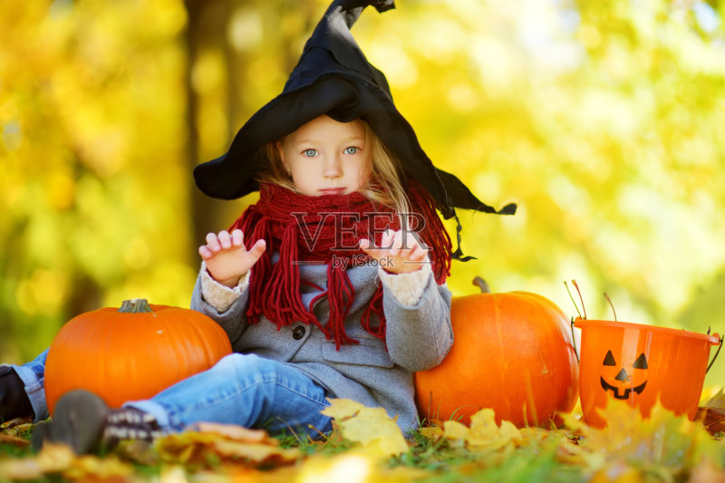 可爱的小女孩穿着万圣节服装在秋天的南瓜地里玩耍正版图片素材