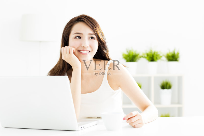 微笑的年轻女子,手提电脑在客厅正版图片素材