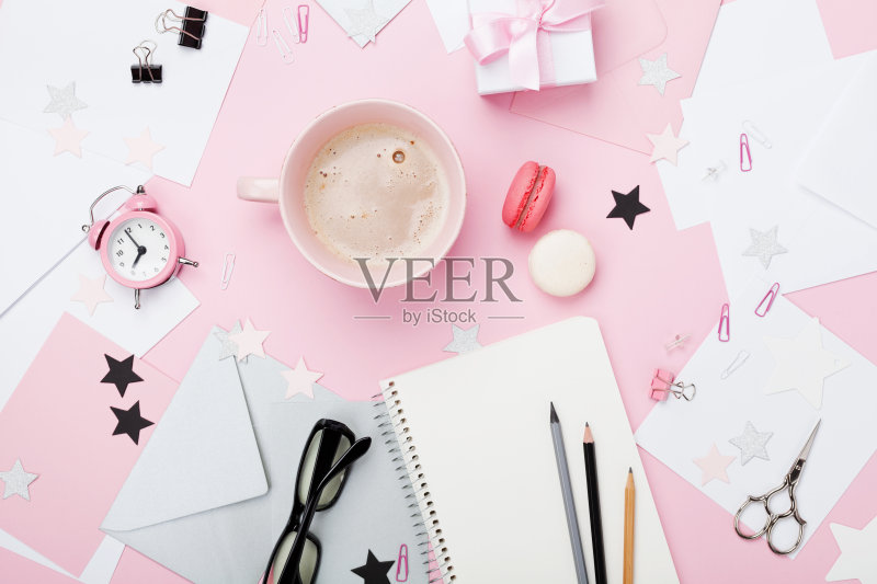 时尚粉色女性职场背景。咖啡,杏仁饼干,办公用品,礼物和写博客用的干净笔记本。正版图片素材