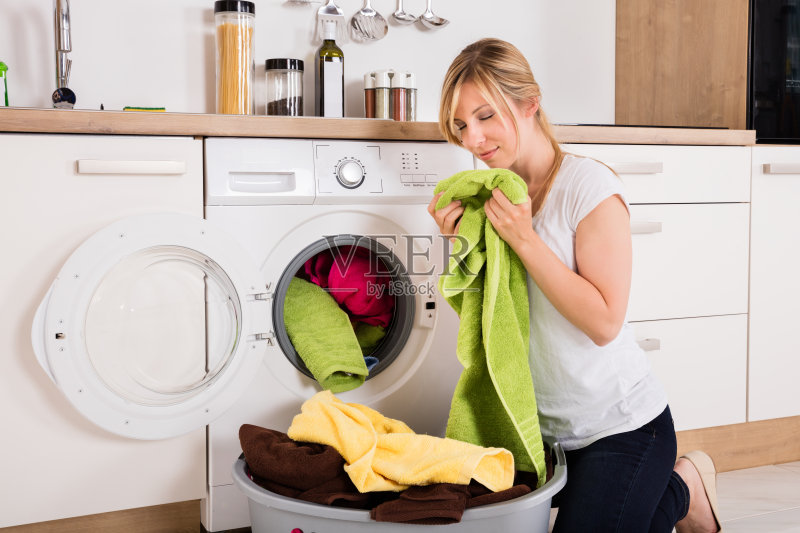 女人在洗衣机旁闻洗过的衣服正版图片素材