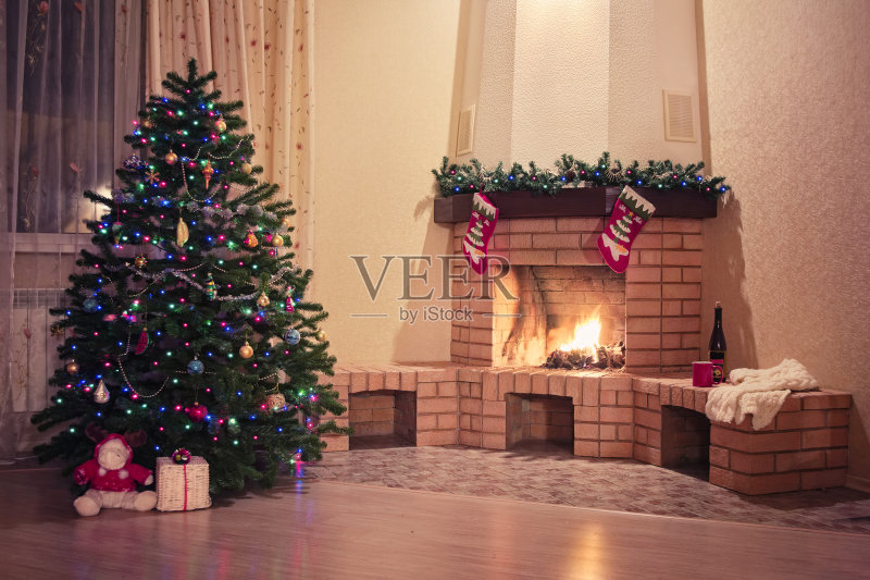 壁炉前的圣诞树上挂着酒瓶正版图片素材