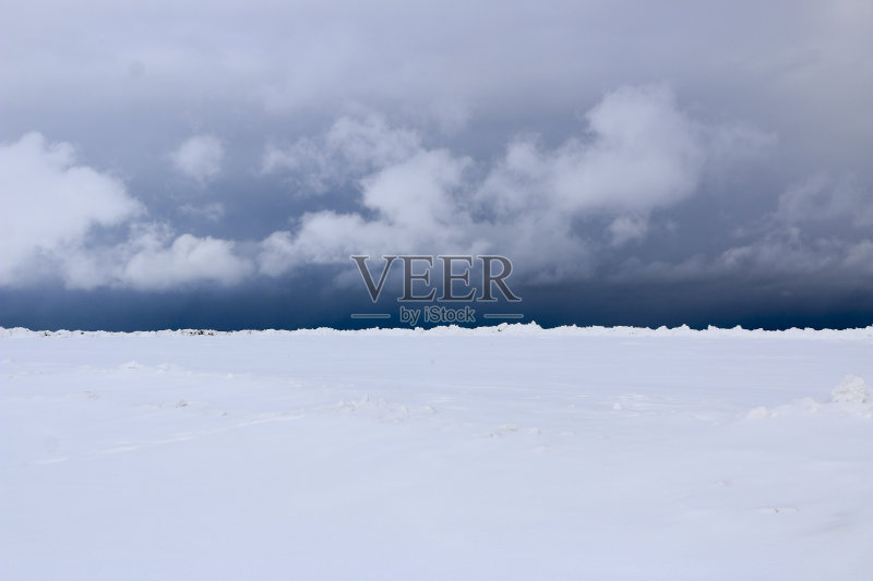 雪的领域。平原上覆盖着白雪,蓝天下有厚厚的白云。在下雪、暴风雨、暴风雪之前。暴风雪的预兆。预计将有暴风雪。正版图片素材